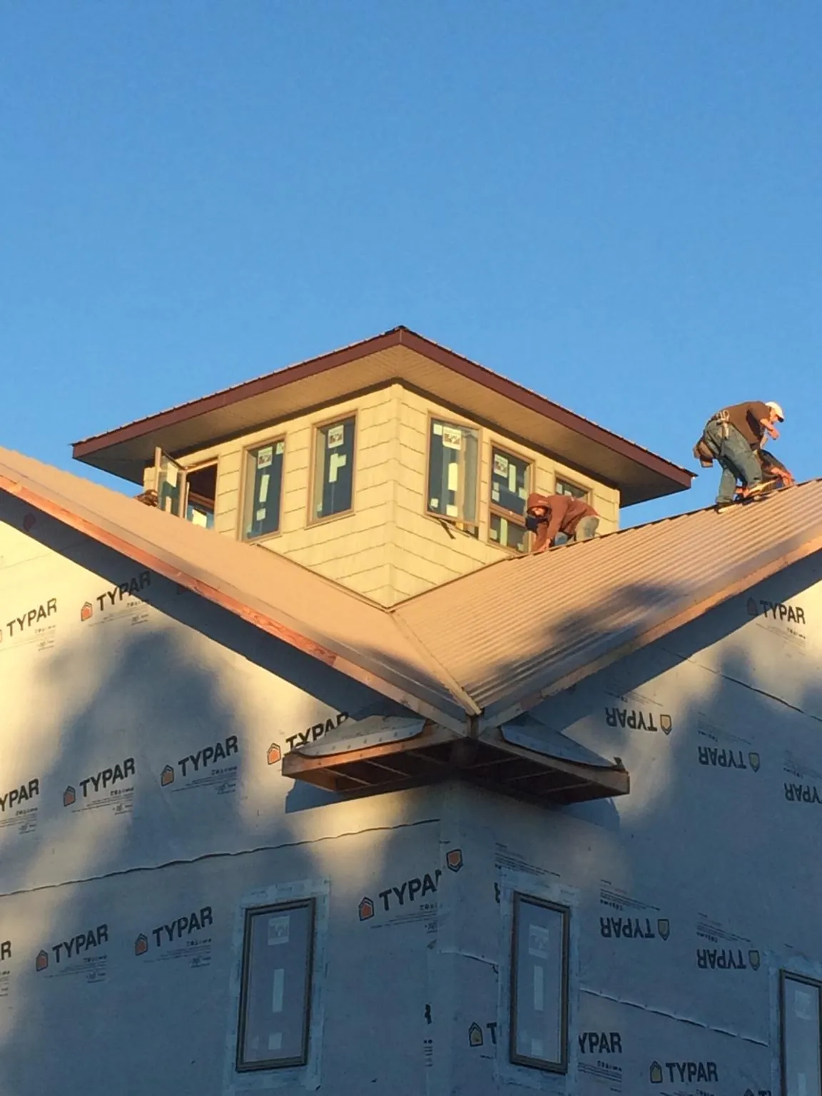 Roofers working around a rooftop cupola on a new metal roof at sunset — Roof Waterproofing in Elizabethtown by Roofing Brothers
